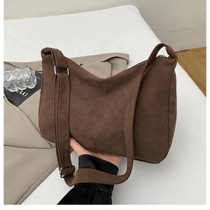 Close-up of brown suede tote bag with adjustable silver buckle and matte texture detail