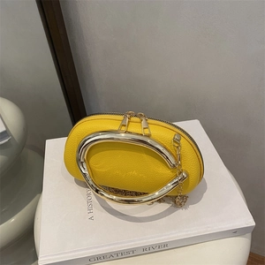 Modern yellow pebble leather crossbody bag with oversized gold handle and chain strap
