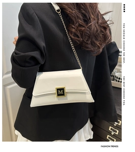 Detail of white leather shoulder bag with gold M-logo buckle and metal chain strap