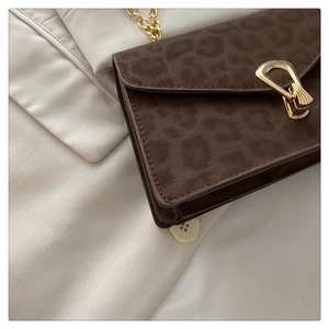 Detail of leopard print suede bag with elegant gold metal lock and chain strap