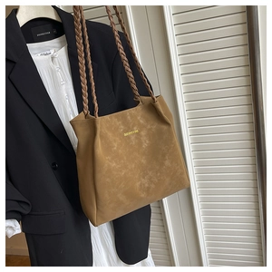 Close-up of khaki tote bag with dual braided straps and gold lettering on premium faux suede
