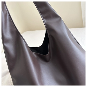 Close-up of high-quality dark brown leather texture and stitching on tote bag