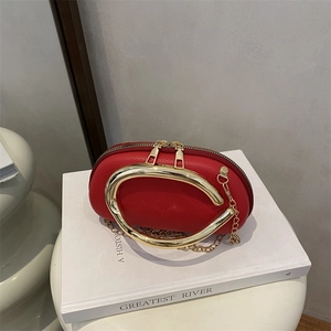 Red pebbled leather oval crossbody bag with distinctive large gold ring handle and chain