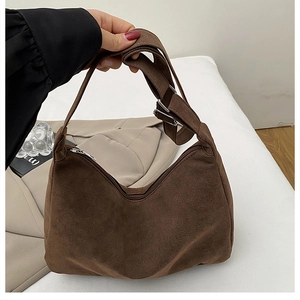 Detail of brown faux suede tote bag featuring adjustable strap buckle and zipper closure