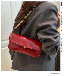 Détail du sac d'épaule en cuir verni rouge avec bandoulière chaîne dorée sur mannequin