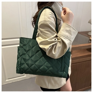 Detail of dark green quilted tote bag with diamond lattice pattern and padded texture