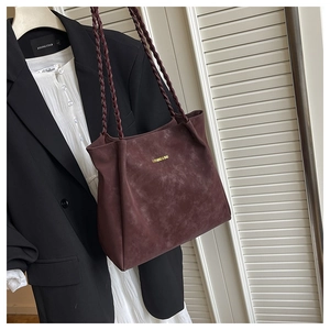 Close-up of wine red suede tote bag featuring woven straps and golden logo print