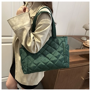 Detailed side view of green quilted tote bag showing texture and side pocket