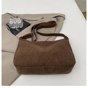 Detail view of the brown frosted tote bag texture on a beige suit with a book