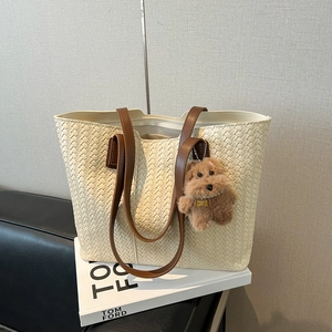 Cream vintage woven tote bag with brown straps and cute plush dog charm on a clean background