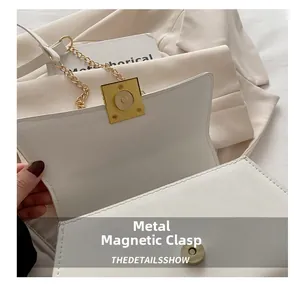 Detail of golden magnetic clasp and metal chain on minimalist cream shoulder bag