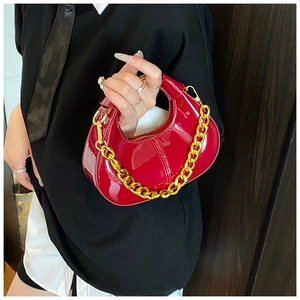 Detail of red patent leather moon bag with glossy finish and gold chain strap