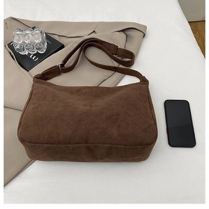 Detail of a brown suede shoulder bag with vertical stitching and adjustable strap
