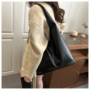Minimalist black tote bag in soft synthetic leather shown worn as a shoulder bag