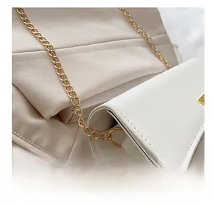 Detailed close-up of golden metal chain link and stitching on a white pillow shoulder bag