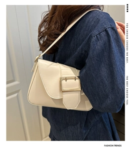 Détail du sac baguette blanc crème avec une grande boucle dorée élégante sur le rabat