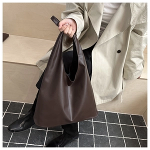 Detail view of large dark brown tote bag worn with beige trench coat for a minimalist look