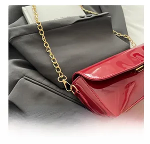 Détail du sac à main en cuir verni rouge avec texture brillante et crochet en métal doré