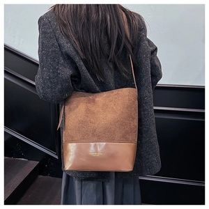 Close-up of brown suede and leather bucket bag showing fine stitching and texture