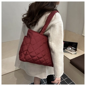 Detailed close-up of wine red quilted tote bag showing rhombus stitching and side pocket