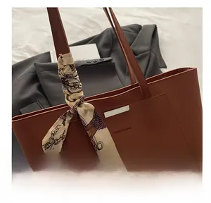 Détail d'un sac cabas en cuir marron foncé avec texte mode et accessoire foulard en soie