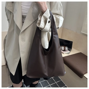Deep brown large hobo tote bag shown on model wearing a trench coat in a minimalist setting