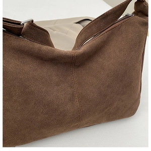 Detail showing the deep brown suede texture and silver metal buckle on a tote bag