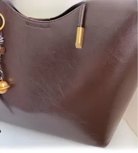 Close-up of soft brown leather tote bag with gold metal rings and stitching details