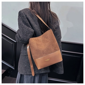 Close-up of brown patchwork bucket bag featuring matte suede and smooth leather textures