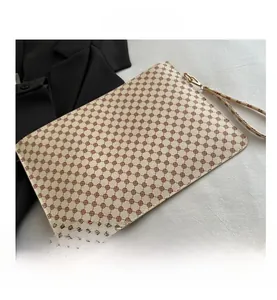 Detail view of the embroidered pattern and detachable hand strap on the fashion pouch
