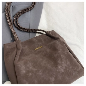 Detail of dark brown tote bag featuring unique woven double shoulder straps and gold logo