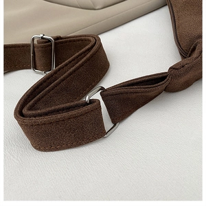 Detail of adjustable silver buckle and stitching on a brown suede shoulder strap