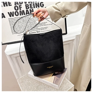 Detail of minimalist black bucket bag featuring suede and leather patchwork design