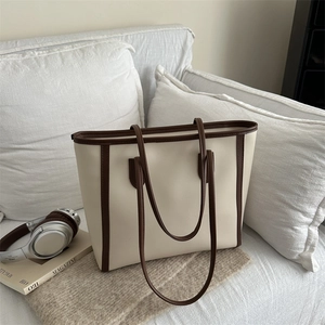Minimalist off-white and brown large tote bag in a lifestyle home setting on a sofa
