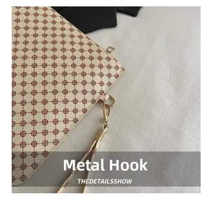 Detailed close-up of light gold metal hook and clover pattern on minimalist handbag