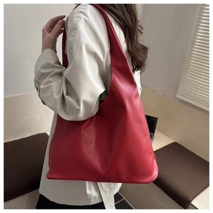 Side view of a large red PU leather tote bag worn with a light coat for casual style