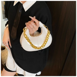 Close-up of white patent leather dumpling bag with chunky gold chain detail
