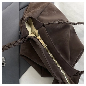 Detail of dark brown faux suede tote with golden zipper and braided rope handle