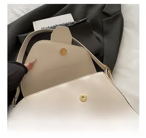 Gros plan du fermoir magnétique doré et du cuir crème sur un sac baguette élégant