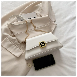 Detailed close-up of white leather handbag with golden M-buckle and chain strap