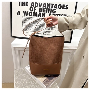 Detail of brown leather and suede bucket bag with gold lettering logo on art books