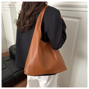 Close-up of caramel brown hobo bag showing textured matte leather and wide strap detail