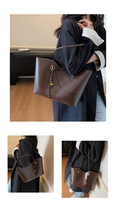 Detailed view of dark brown leather tote with golden ring hardware and decorative charms