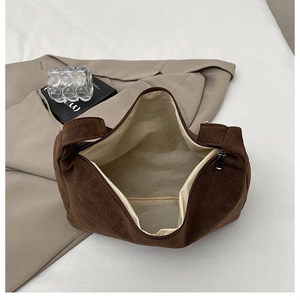Detail of deep brown suede handbag interior showing light beige lining and metal zipper