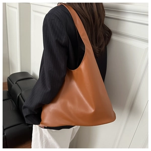 Brown faux leather tote bag worn by model, showcasing large capacity and minimal design