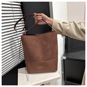 Detail of dark brown leather and suede bucket bag showing contrast texture and logo