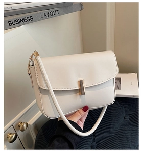 Close-up of cream structured shoulder bag featuring a gold cylindrical metal clasp