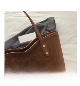 Detail view of leopard print tote bag featuring faux suede texture and leather handles
