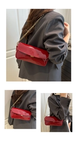 Détails du sac baguette en cuir verni rouge avec bandoulière chaîne dorée et fini brillant