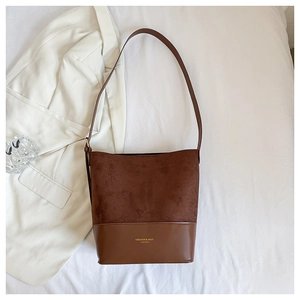 Detail of contrast textures on a dark brown underarm bag featuring gold lettering